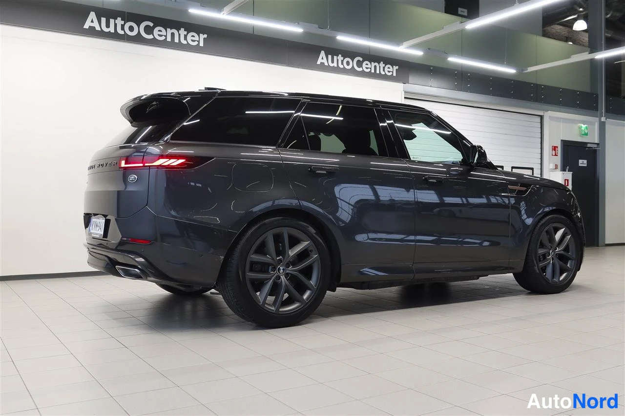 Takaviisto: Tummanharmaa maasturi takaa-alaviistokuvassa AutoCenter-hallissa, takavalo ja pyörät näkyvissä.