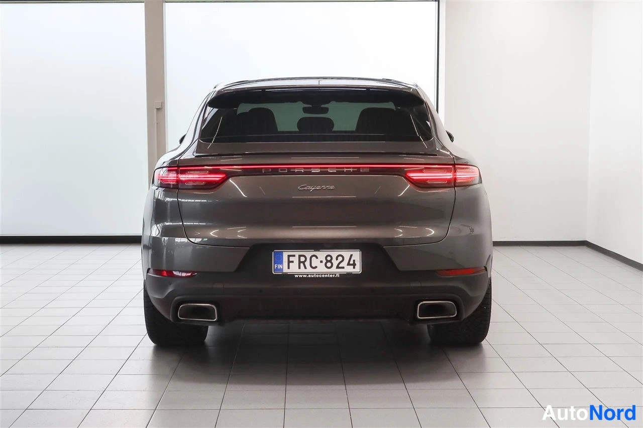 Takaa: Auton takaosa suoraan takaa; tummanharmaa coupé-SUV, yhtenäinen takavalojauo, PORSCHE- ja Cayenne-teksti takaluukussa, rekisterikilpi, kaksi pakoputkea.