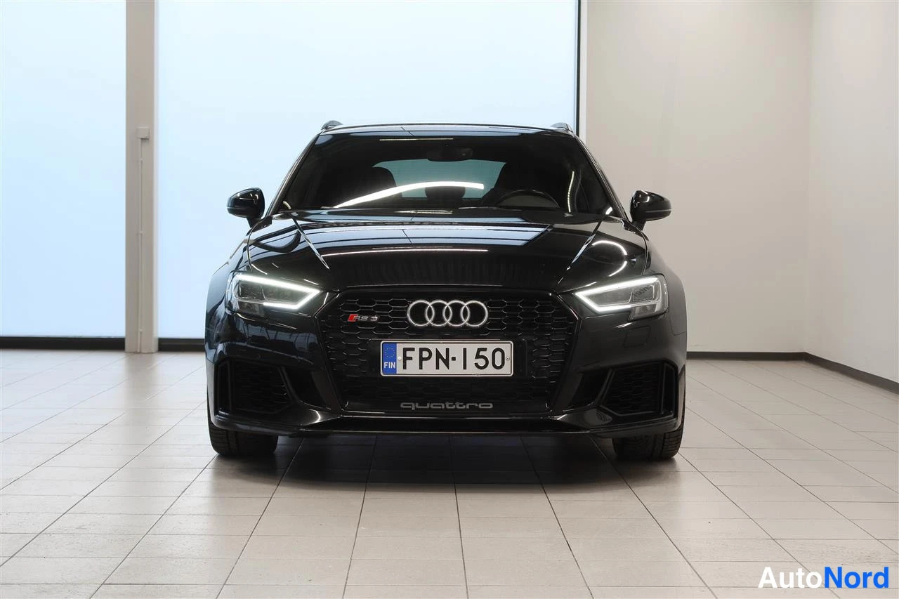 Edestä: Mustan Audi RS 3 Sportbackin suora etuotku näyttää etusäleikon, FP N-150 -rekisterikilven ja LED-etuvallot sisätiloissa.