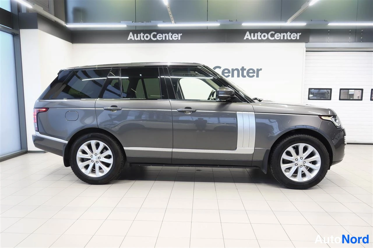 Takaviisto: Land Rover Range Rover -maasturin takaosa ja kylki näkyvät sivukulmassa showroomin valkoisella lattialla, tummanharmaa kori ja hopeiset vanteet.