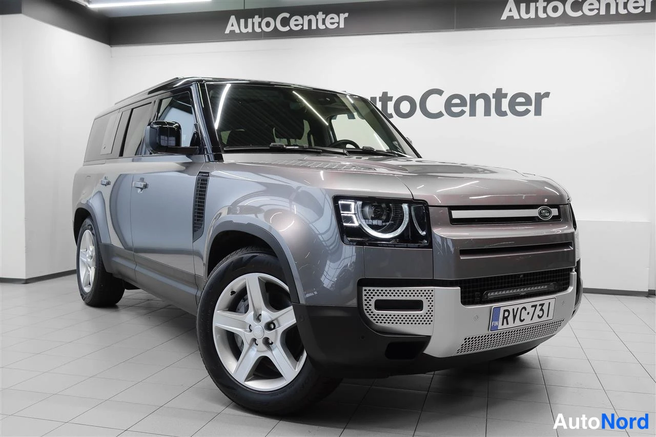 Etuviisto, nokka oikealle: Harmaa Land Rover Defender -maasturi etukulmasta, rekisteritunnus, myyntihallissa.