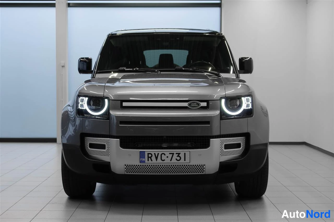 Edestä: Land Rover Defenderin etunäkymä suoraan edestä, LED-ajovalot päällä, rekisteritunnus.