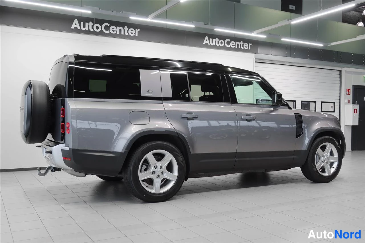Takaviisto: Land Rover Defender 130:n takaosakulmakuva sisätiloissa, harmaa kori, musta katto, takarenkaanhaltija ja rekkauskytkin näkyvät.