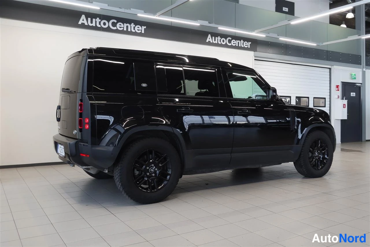 Takaviisto: Mustan Land Rover Defenderin takakulmanäkuva sisätiloissa, takaosa ja vasen kylki näkyvissä.