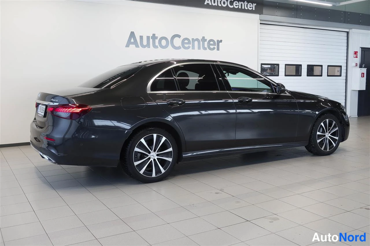 Takaviisto: Tumma Mercedes-Benz-sedan takaviistosta vasemmalta, punaiset takavalot, rekisterikilpi ja kromilista ikkunoissa.