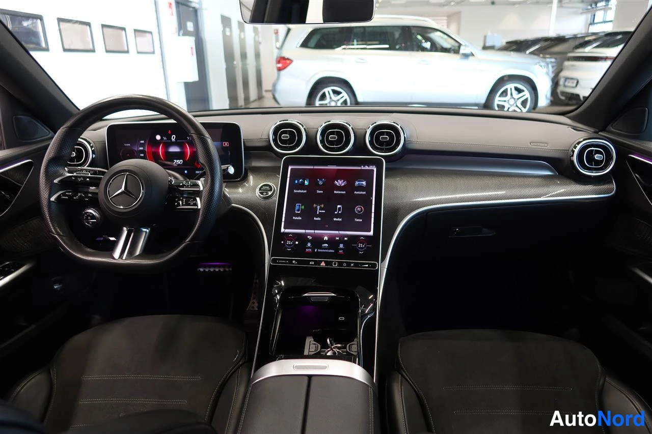 Sivulta: Mercedes-merkkisen auton kojelauta ja keskinäyttö keskikonsolineen, paikallaan oleva nopeusnäyttö 250 km/h ja valikot näkyvissä.