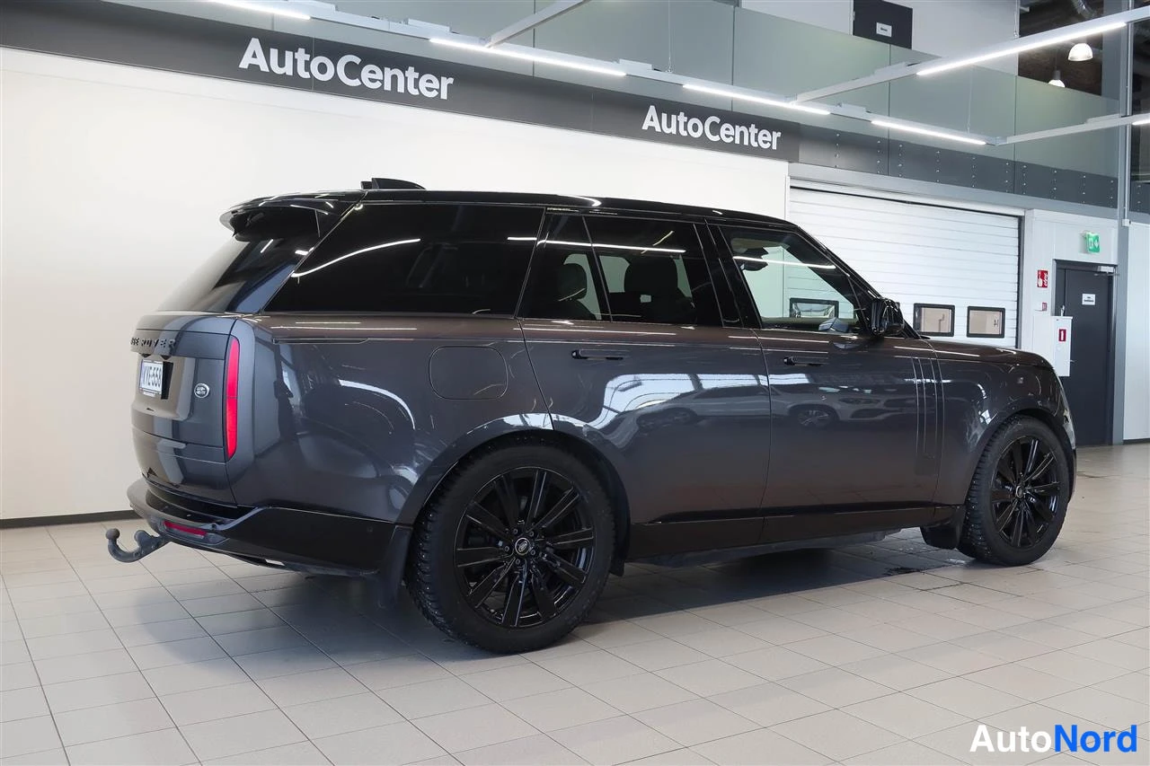 Takaviisto: Tummanharmaan Land Rover Range Roverin takakulmakuva sisätiloissa; näkyvissä takavalot, perävaunukoukku ja mustat kevytmetallivanteet.
