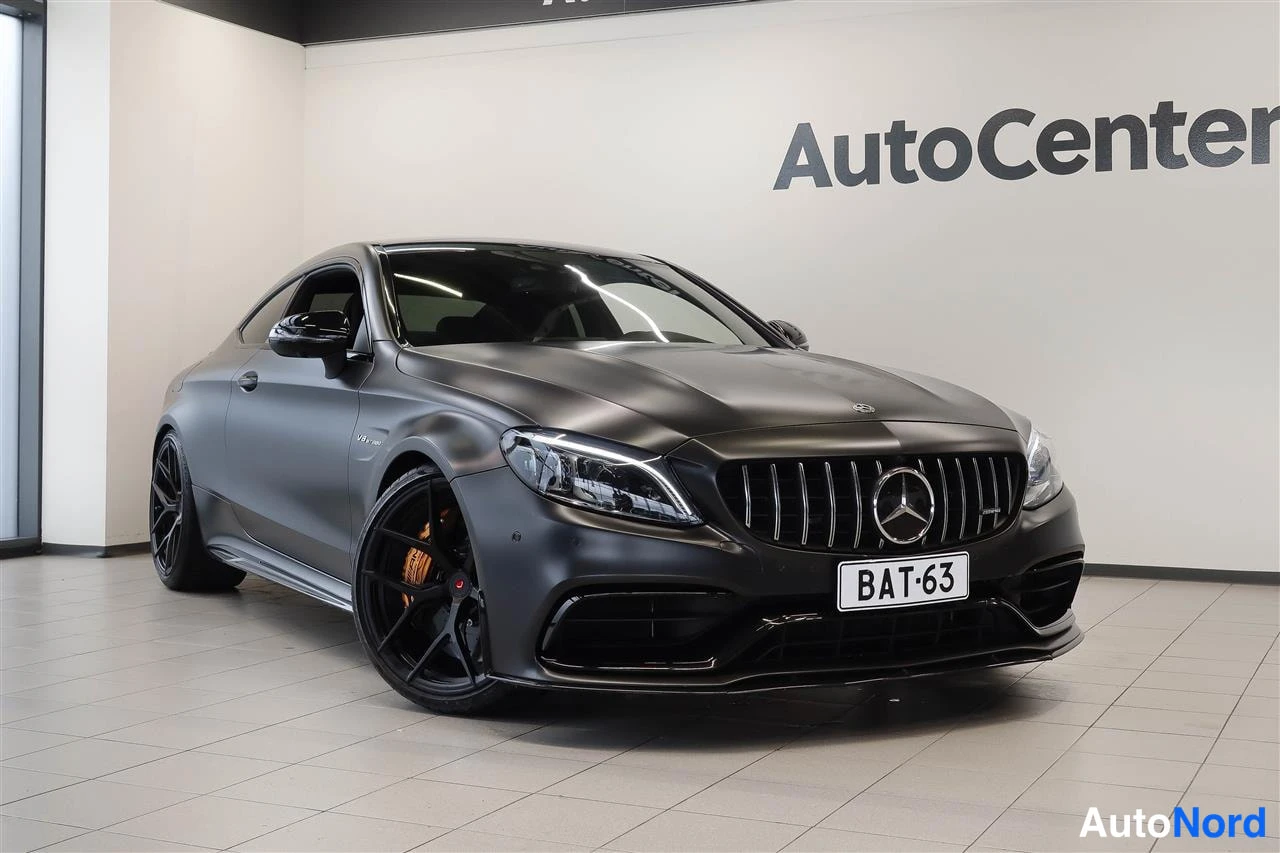 Etuviisto, nokka oikealle: Musta Mercedes-Benz coupe kolmannelta etuviistöltä autotallissa, etusäleikkö ja keskustelmoitus näkyvät.
