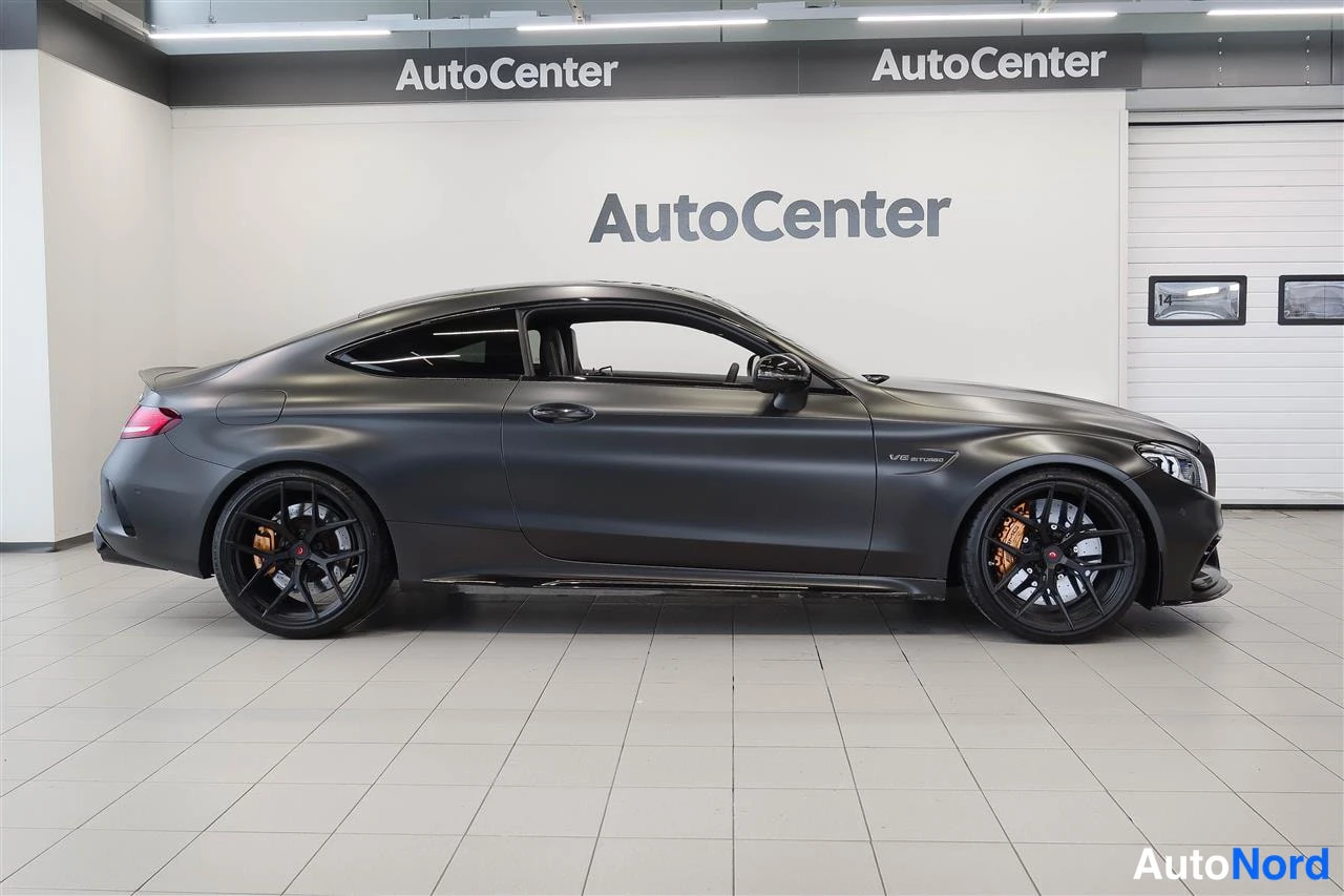 Sivulta: Harmaa Mercedes-Benz coupe sivuprofiilista oikealta katsottuna autotallin parkkipaikalla.