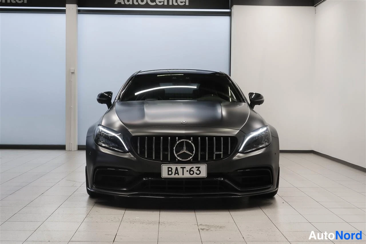 Edestä: Harmaa Mercedes-Benz coupe suoraan edestäpäin, säleikkö ja rekisterikilpi erottuvat.