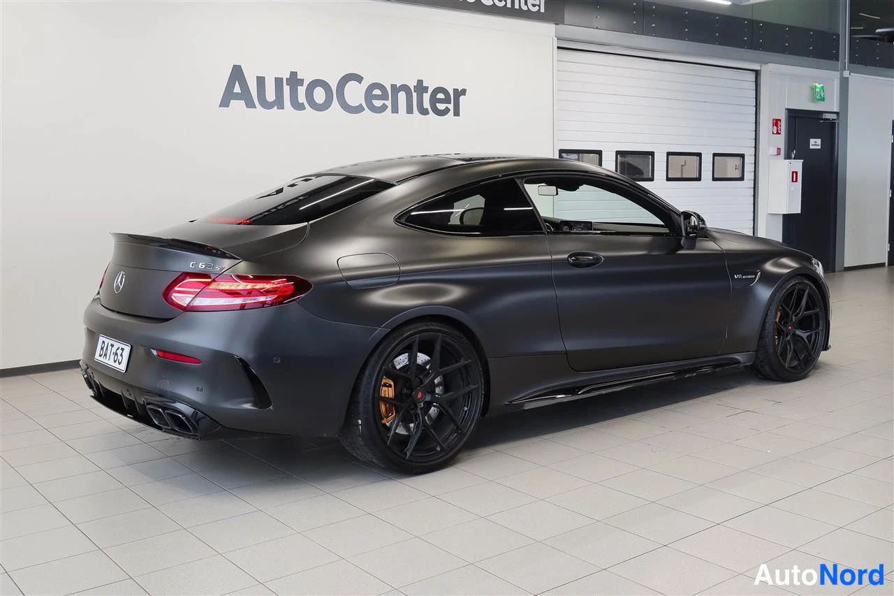 Takaviisto: Tummanharmaa Mercedes-Benz C 63 -coupe takaa oikealta nähtynä myyntihallissa.