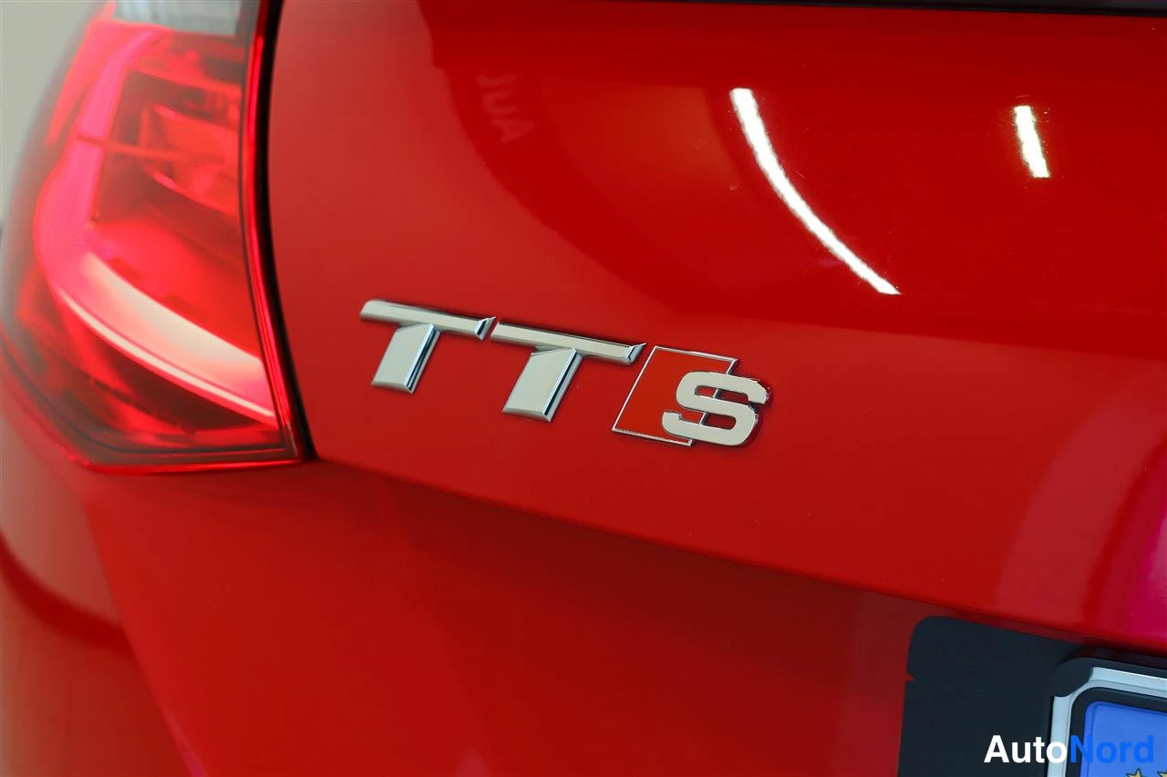 Takaa: Punaisen auton takaosa lähikuvassa: TTS-merkki ja takavalo.