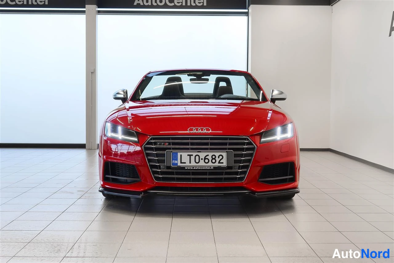 Edestä: Punainen Audi TTS Roadster suoraan edestä sisätiloissa, rekisteritunnus, etuvalot päällä.