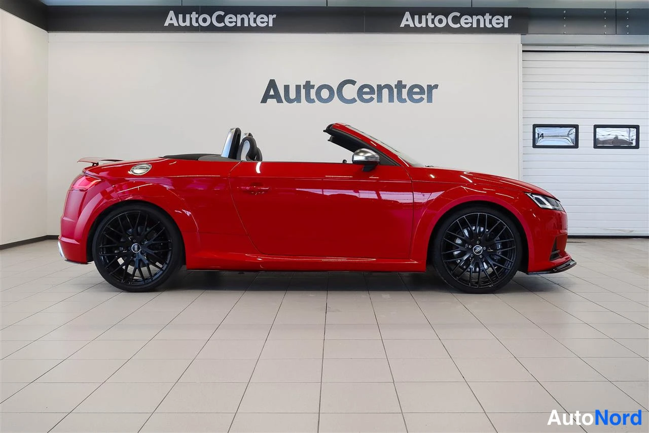 Etuviisto, nokka oikealle: Punainen Audi TTS Roadster sivulta sisätiloissa, avattu katto ja mustat vanteet.