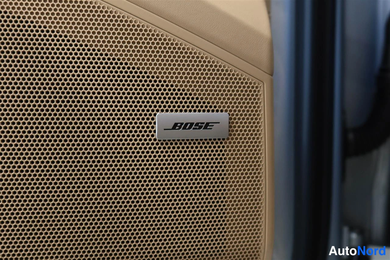 Yksityiskohta: Bose-merkitty kaiuttimeen verkko beigeässä sisäpanelissa.