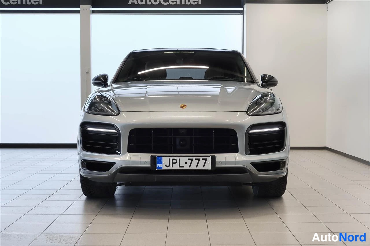 Edestä: Hopeanvärinen henkilöauto edestä, rekisterikilpi.