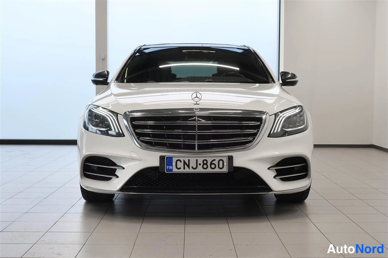 Edestä: Valkoisen Mercedes-Benz S-luokan sedanin suora etänäkymä, rekisterikilpi.