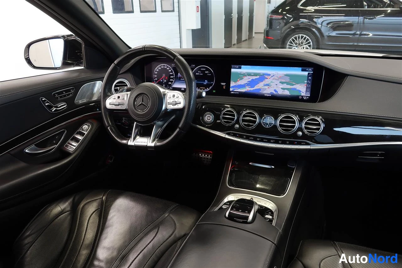Edestä: Mustan Mercedes-Benzin matkustamisto sisäapäältä: ohjauspyörä, digitaalinen mittaristo, kartta näyttävä keskinäyttö ja pyöreät ilmastointivento.