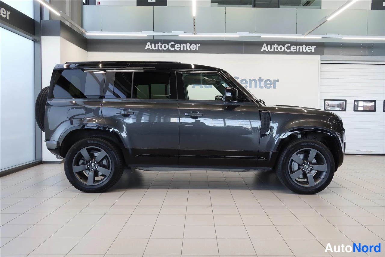 Sivulta: Land Rover Defender, tummanharmaa, sivulta vasemmalta, takana varapyörä.