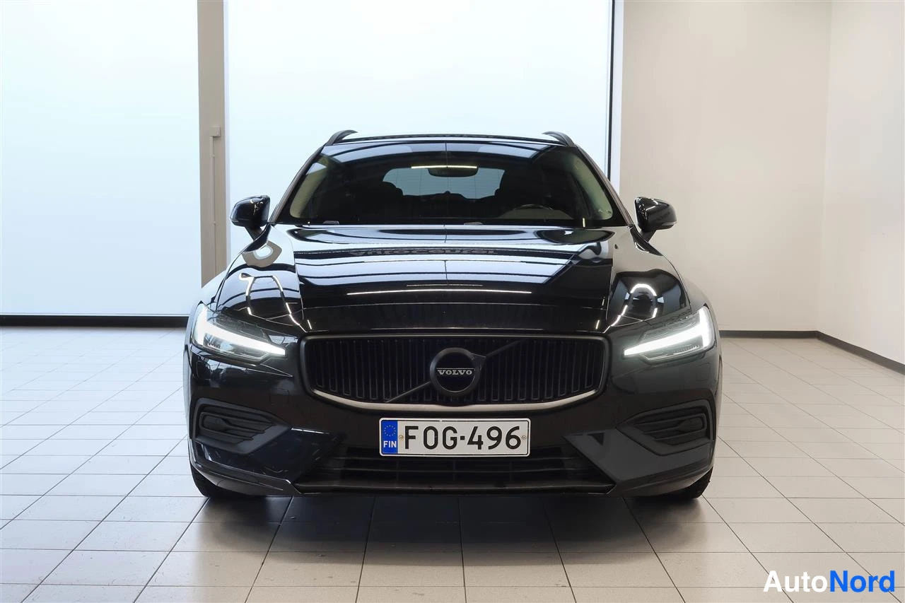 Edestä: Mustan Volvo V60:n etupää suoraan edestä, Volvo-merkki konepellillä ja rekisteritunnus.