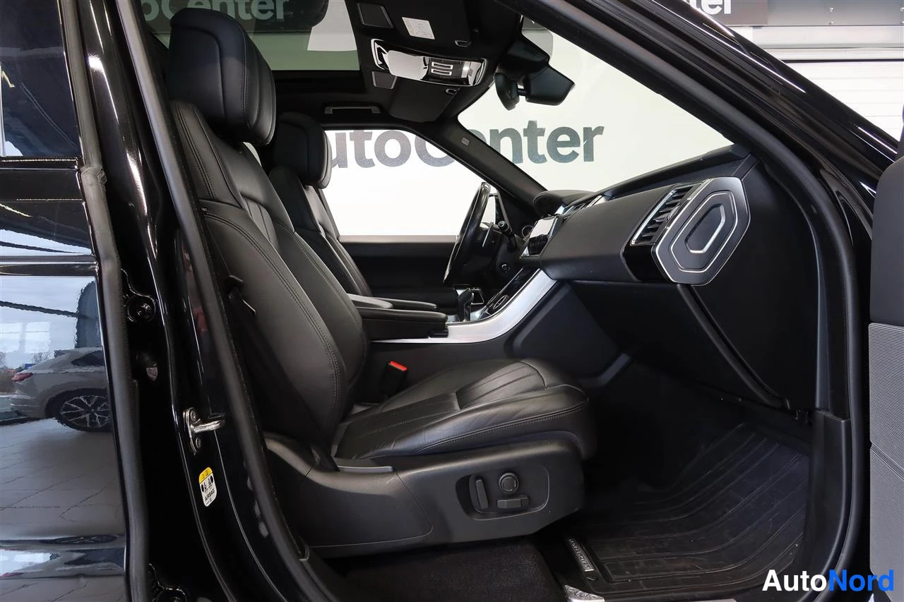 Muu: Avautunut etuovipari: kaksi mustaa nahkaistuinta, kojelauta ja panoramakaton etuosa; taustalla AutoCenter-taulu.