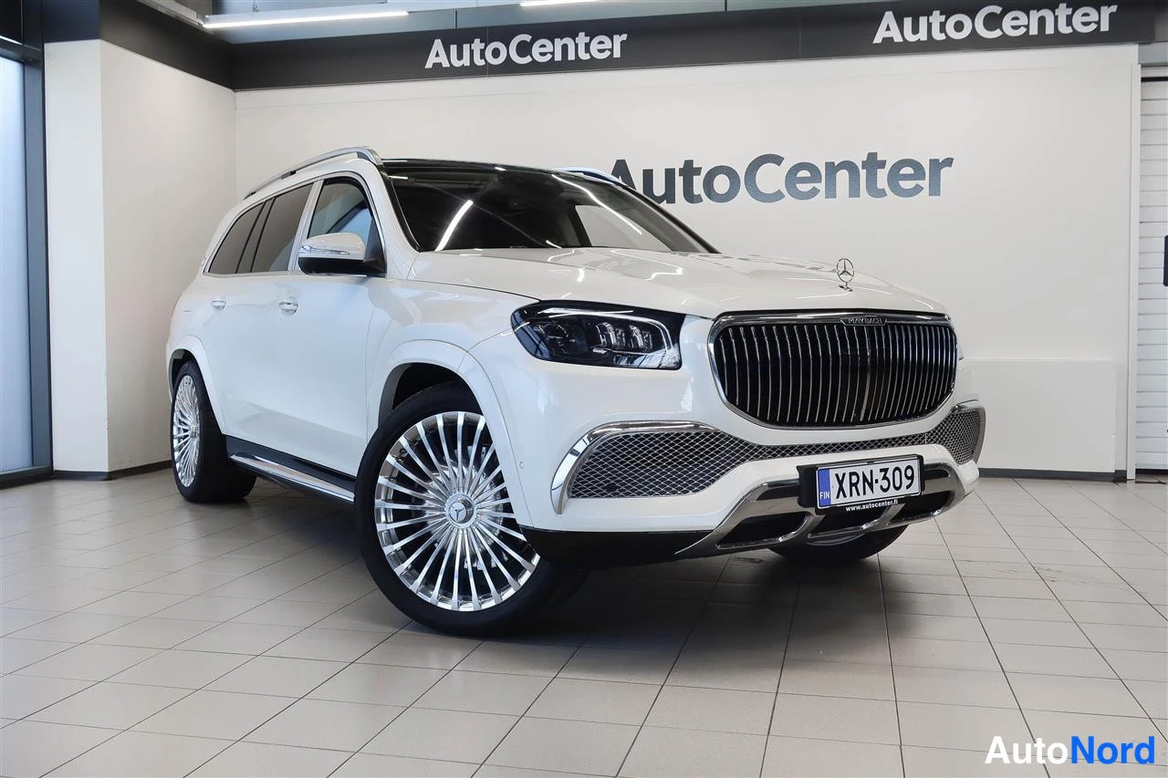 Etuviisto, nokka oikealle: Valkoinen Mercedes-Benz GLS Maybach -maastoauto vinosta edestä oikealta kuvattuna, rekisterikilpi, moni­sieppovanteet, AutoCenter-hallissa.