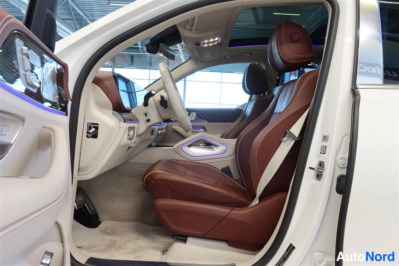 Yksityiskohta: Mercedes-Benzin etuistuin ja lukuosasto ruskeapunaisella nahalla, valohiipivä sisävalaistus ja panoraamakatto näkyvissä.