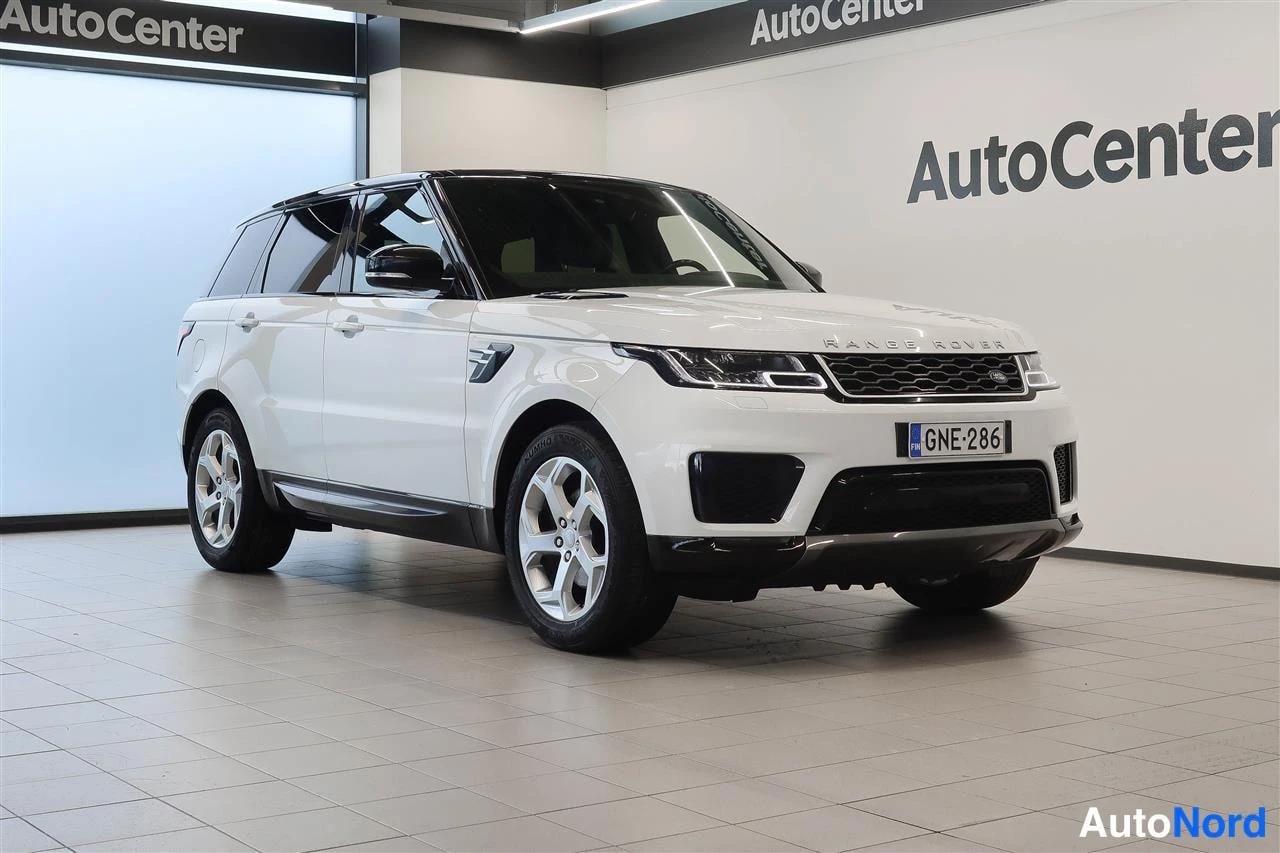 Etuviisto, nokka oikealle: Valkoinen Land Rover Range Rover Sport myymälähallissa, etukulmakuva oikealta; rekisteritunnus.