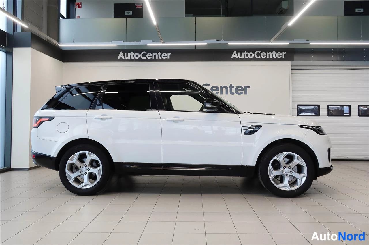 Sivulta: Valkoisen Land Rover Range Rover Sportin sivunäkymä myymälässä, auton oikea kylki kuvassa vasemmalta katsottuna.