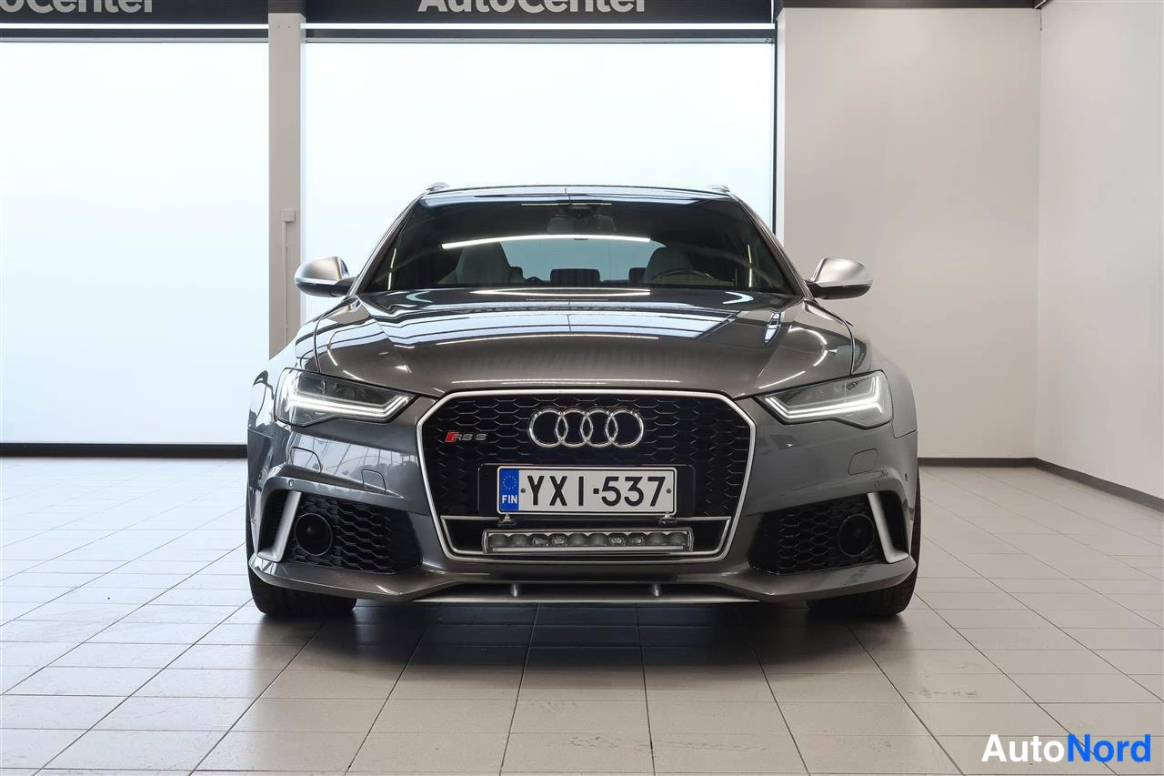 Edestä: Tummanharmaa Audi A6-farmari suoraan edestä, rekisteritunnus, AutoCenter-hallissa.