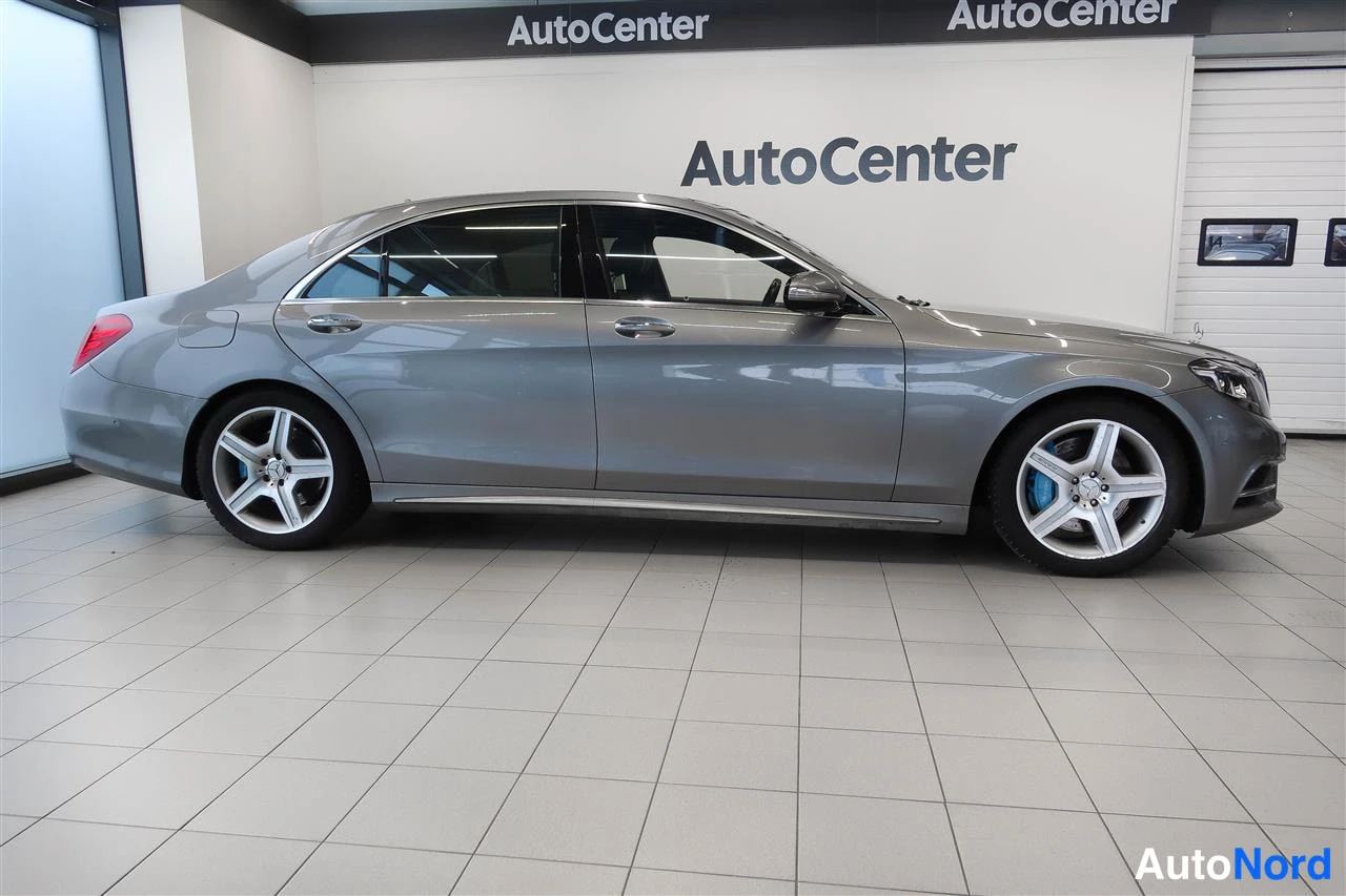 Sivulta: Mercedes-Benz S-sedan profiili oikealta kyljeltä, hopeanharmaa kori ja hopeavat viisipyyhepelliset renkaat.
