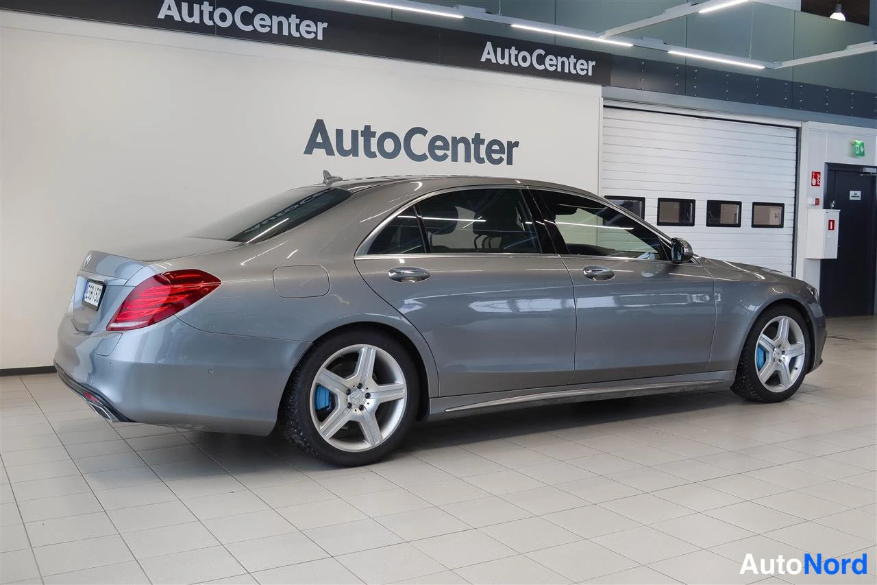 Takaviisto: Mercedes-Benz S-sedan takakulma vasemmalta, hopeanharmaa kori, punaiset takavalot ja takarenkaat.