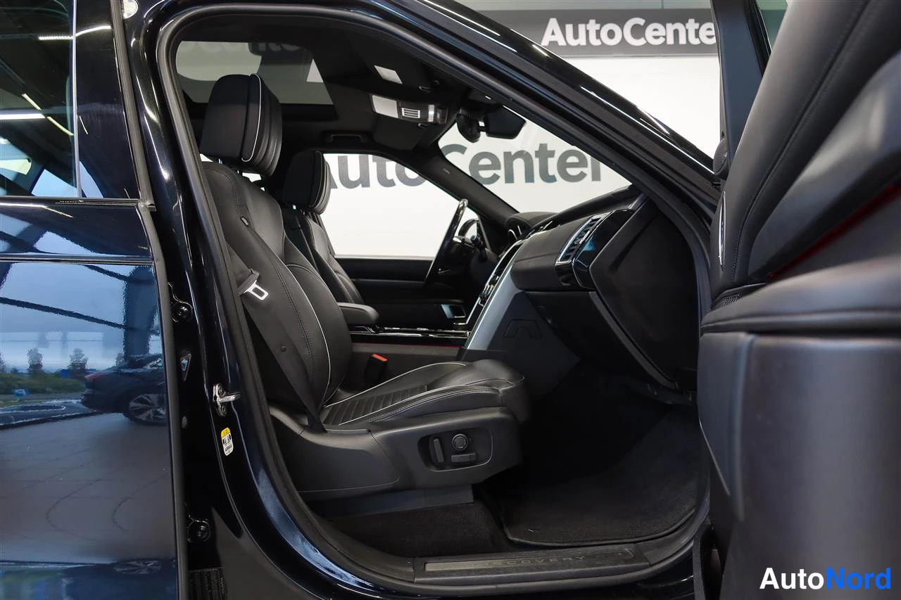 Yksityiskohta: Autojen näyttelytilassa avoimesta etuovesta näkyy musta nahkapenkin etupenkk ja kattoikkuna; taustalla AutoCenter-kyltti.