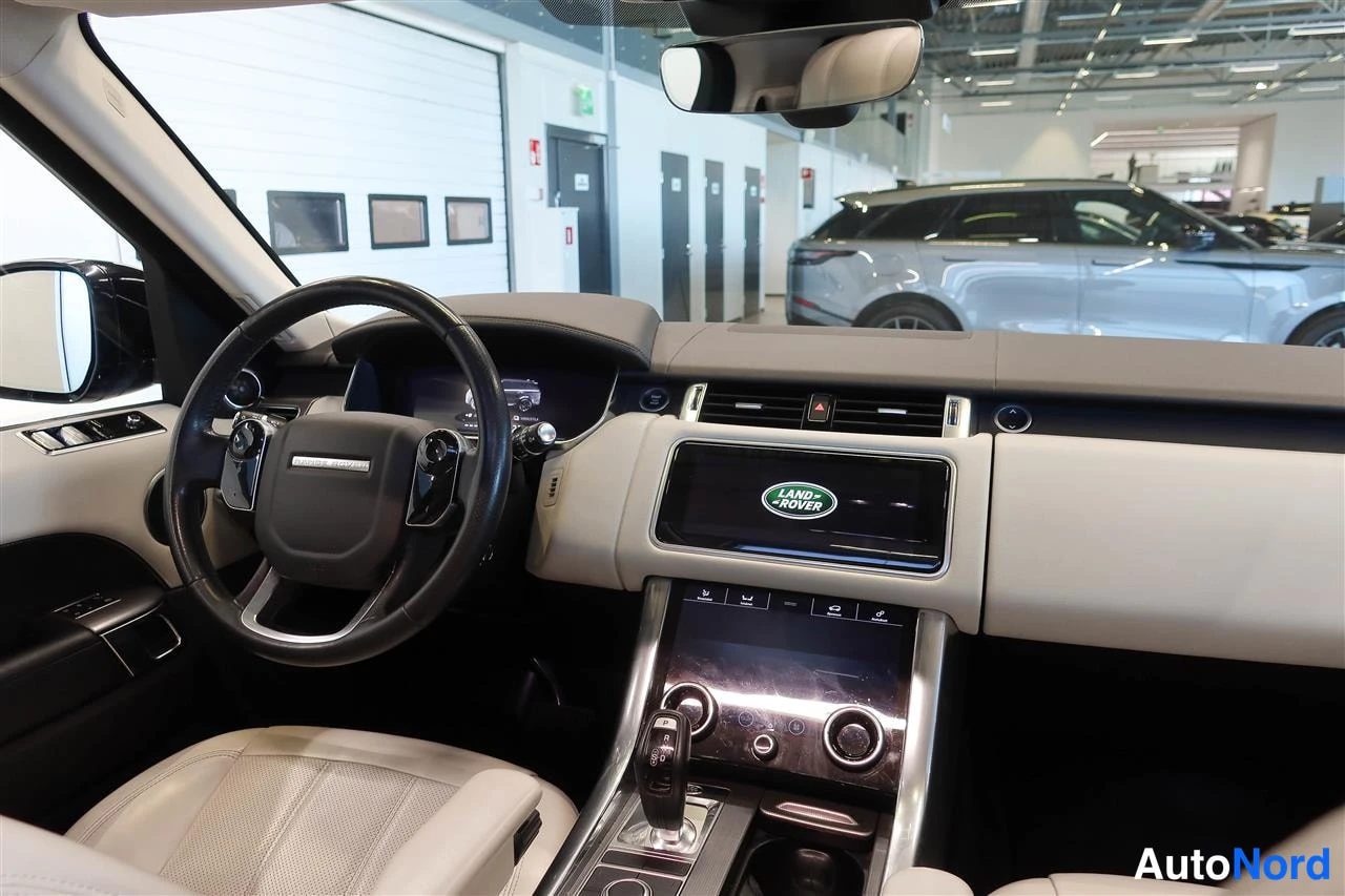 Muu: Kojelauta ja ohjauspyörä näkyvät keskikonsolilla LAND ROVER -kosketusnäytöllä ja vaalealla nahkapinnalla.