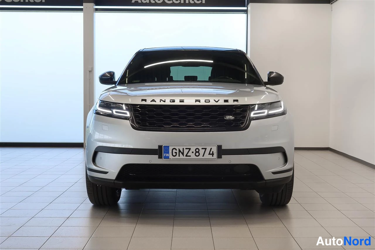 Edestä: Suora etunäkymä hopeisesta Land Rover Range Rover Velarista, rekisteritunnus, autohallissa.