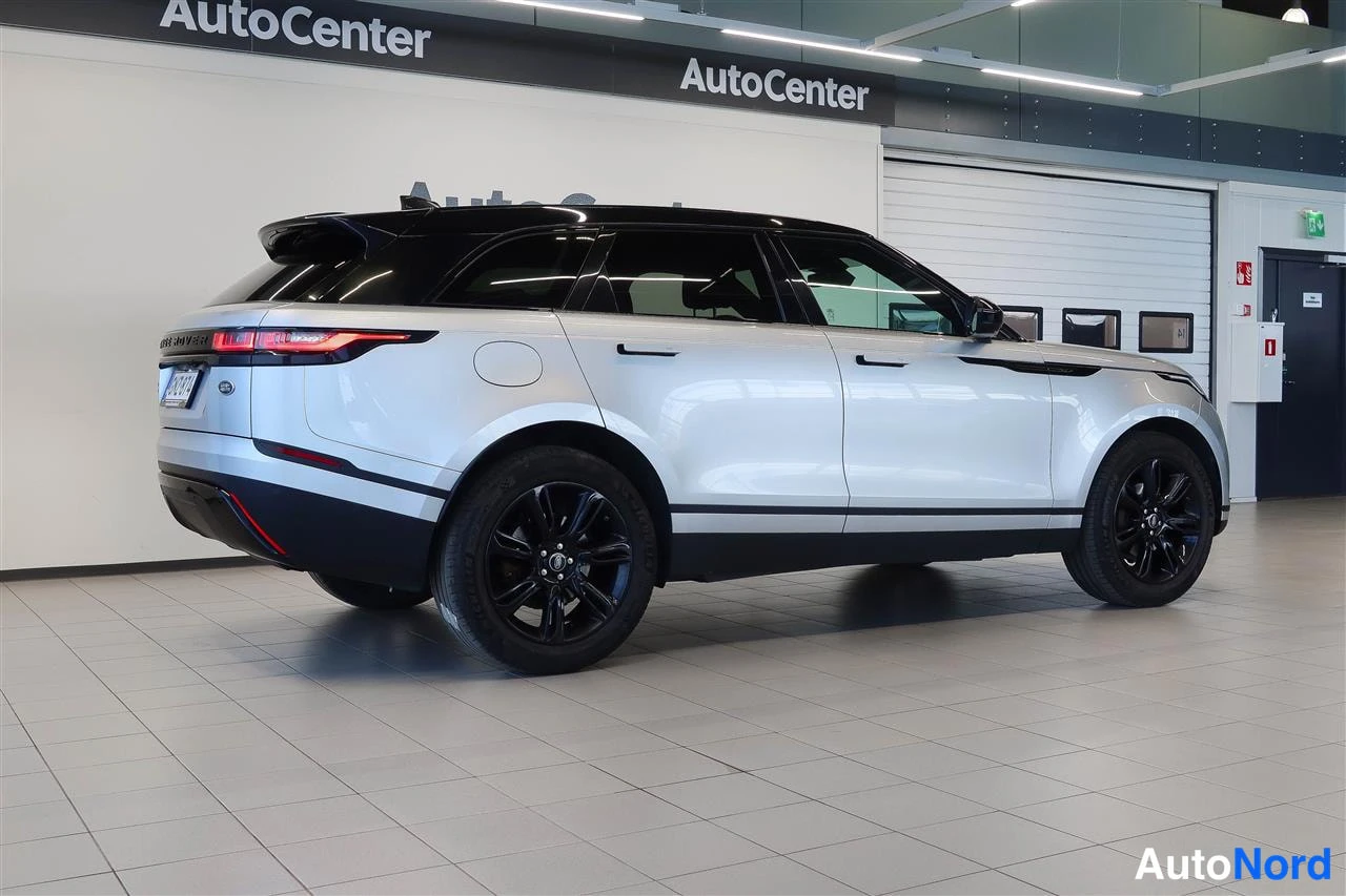 Takaviisto: Hopeanvärinen Land Rover Range Rover Velar takaa kulmasta kuvattuna sisätiloissa, tummat pyörät ja musta katto.