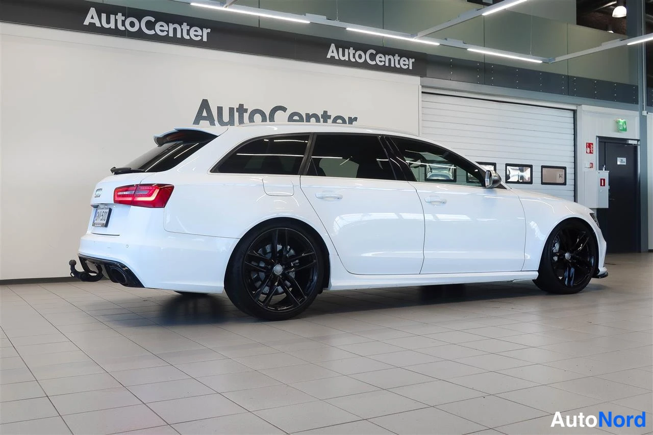 Takaviisto: Auton takakulmanäkuva: valkoinen farmariauto näkyvät takavalot, rekisterikilpi ja mustat vanteet AutoCenter-hallissa.