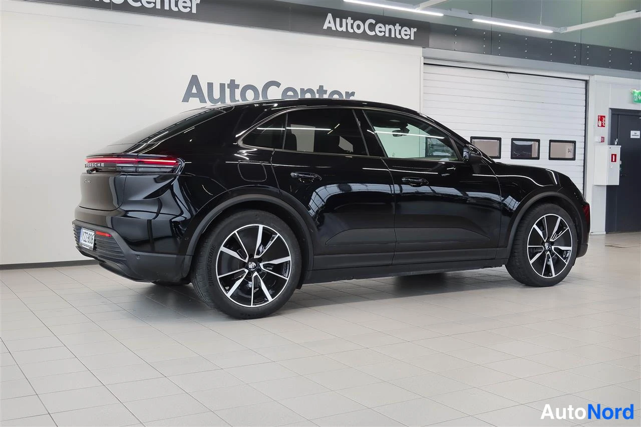 Takaviisto: Musta Porsche Macan -tyylinen coupé-SUV takaviistosta kuvattuna sisätiloissa, takavalot ja vanteet näkyvät.