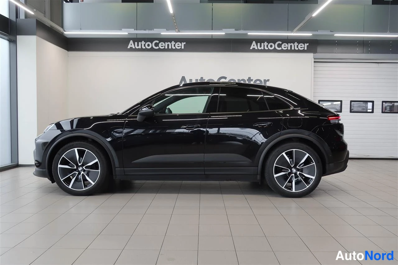 Sivulta: Musta Porsche Macan -maasturin sivuprofiili AutoCenter-hallissa, viisiovinen coupé-mallinen runko ja kaksiväriset kehäkansiopyörät.