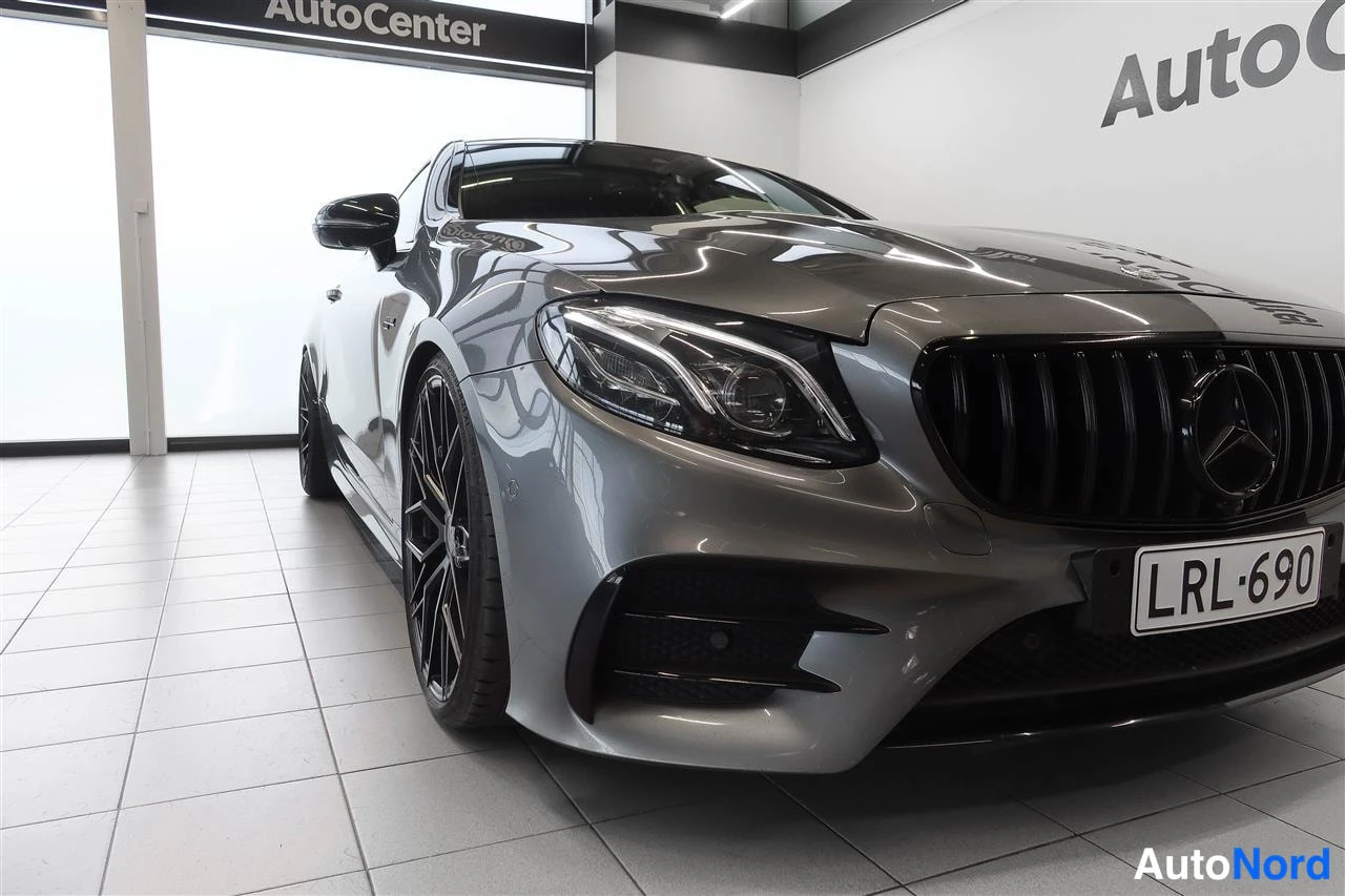 Etuviisto, nokka oikealle: Lähikuva Mercedes-Benz E 53 AMG:n etuosasta, harmaa kori, musta säleikkö ja punainen jarrusatula.