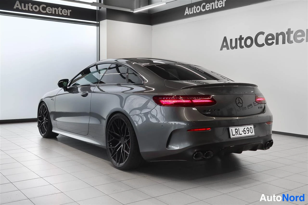 Takaviisto: Harmaan Mercedes-Benz Coupén takakulma oikealta kuvattuna; rekisterikilpi ja neljä pakoputkea näkyvät.
