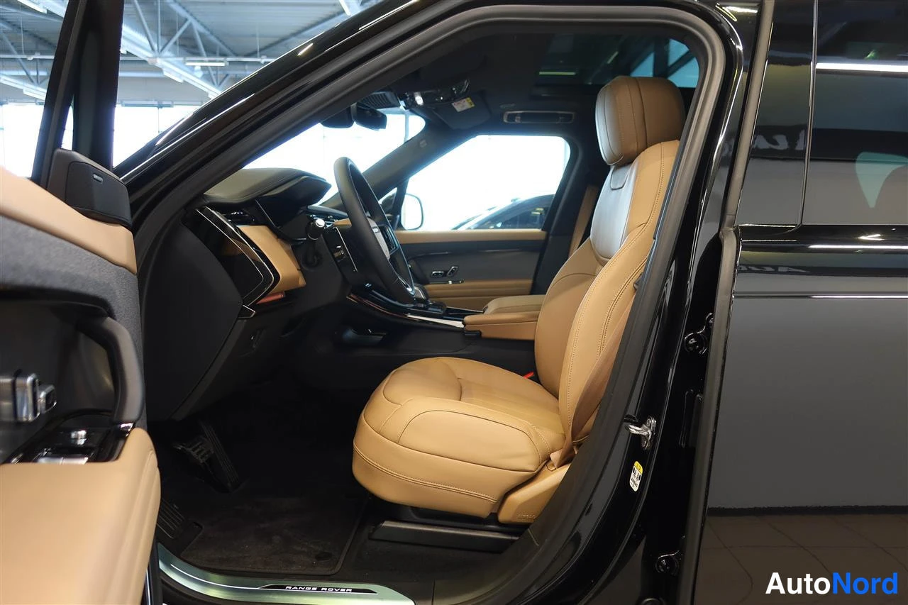 Yksityiskohta: Autojen sisätilan kuljettajan puoli: musta ohjauspyörä, beige turvaosat ja Range Rover -kynnysova.