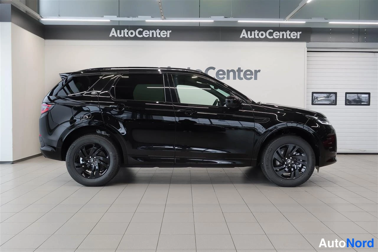 Sivulta: Musta Land Rover Discovery Sport sivulta oikealta, AutoCenter-hallissa