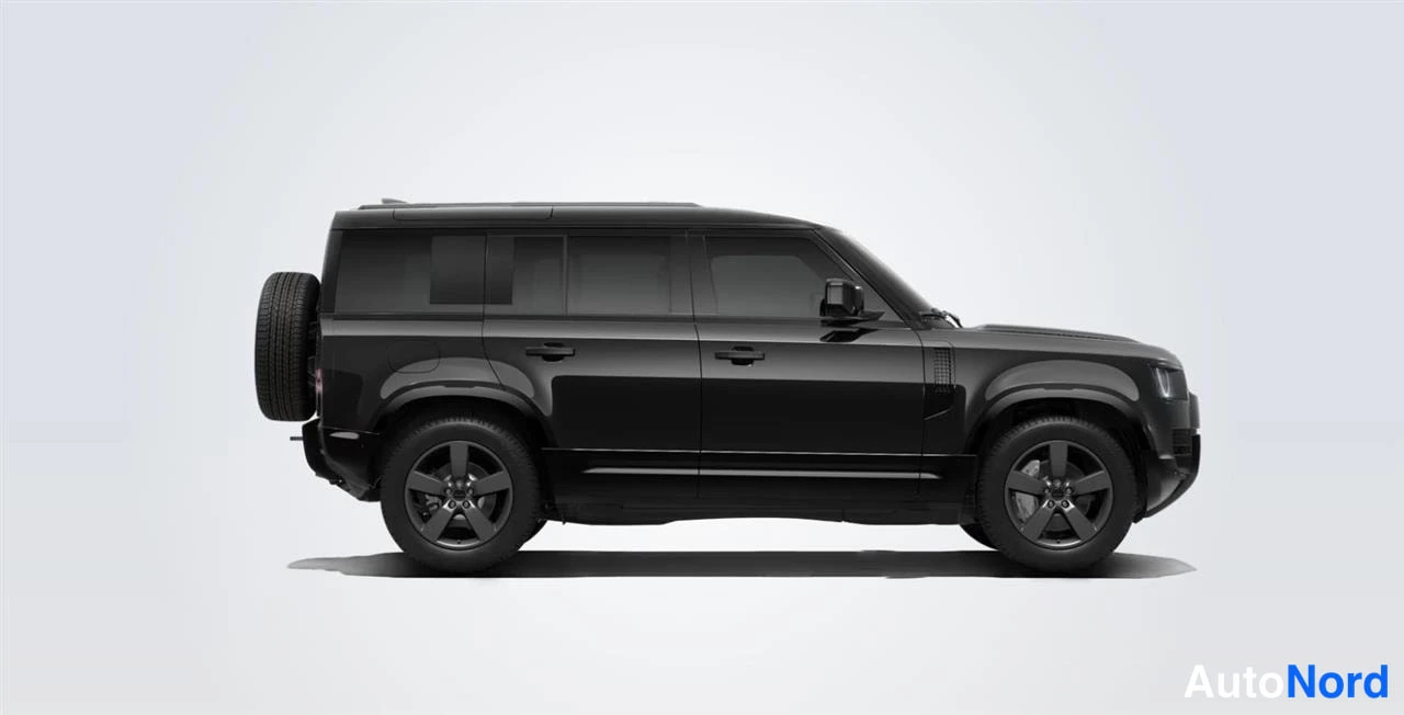 Sivulta: Land Rover Defender 110, musta, sivukuva vasemmalta, takana varapyörä ja pimeät vanteet, vaalea studiovaalea tausta.