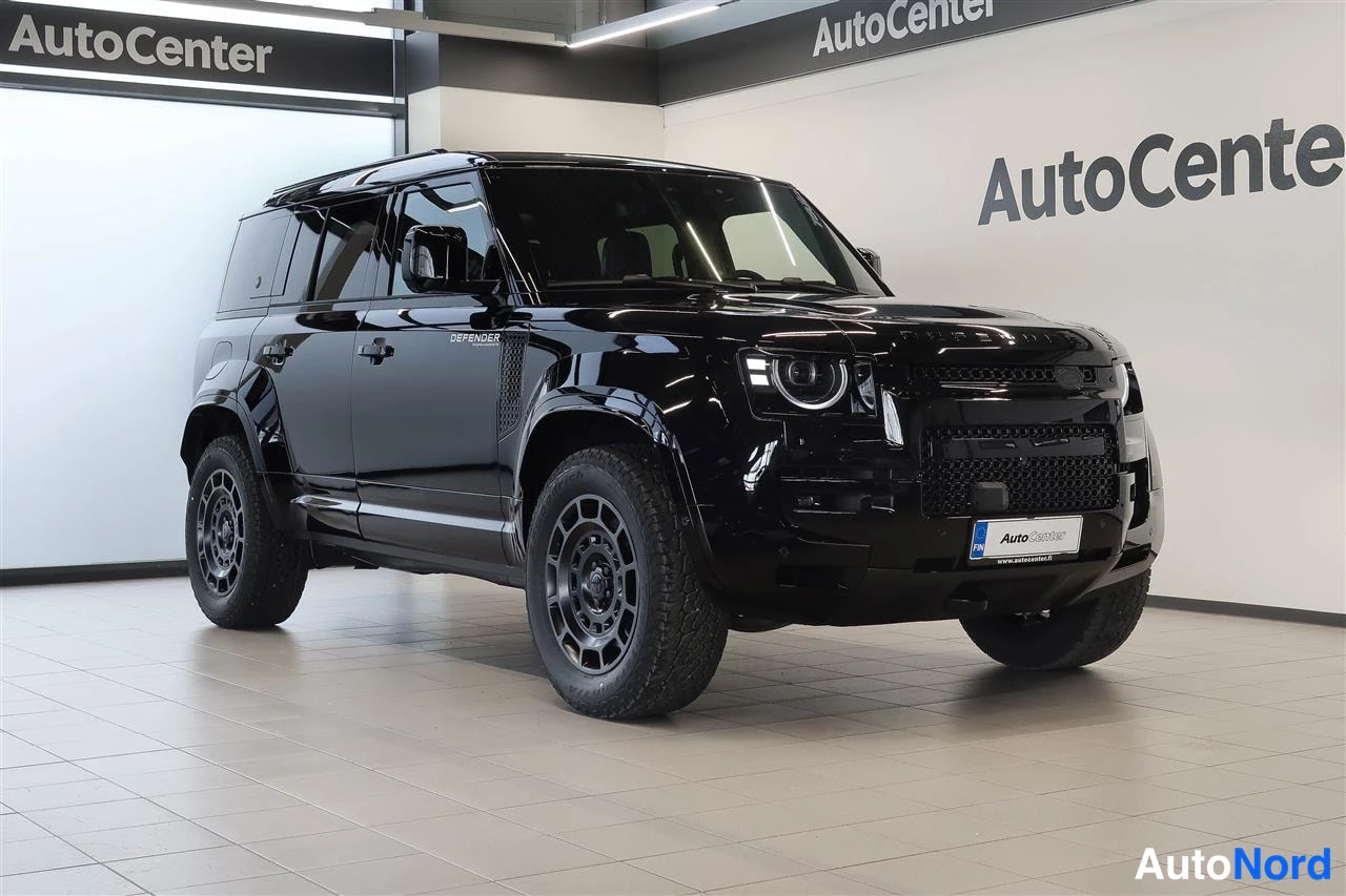 Etuviisto, nokka oikealle: Mustan Land Rover Defenderin etukulmanäyttö Autocenter-hallissa; DEFENDER-kylkiteksti ja etusäleikkö erottuvat.