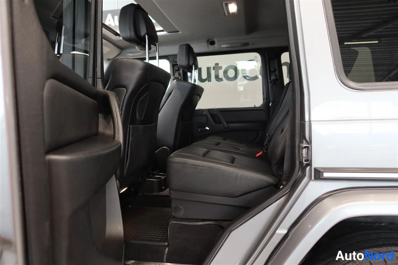 Muu: Takapenkkinäkemys Mercedes-Benz G:n tummasta nahkasisustasta; istuimet ja keskikonsoli näkyvät avatusta takaovesta.