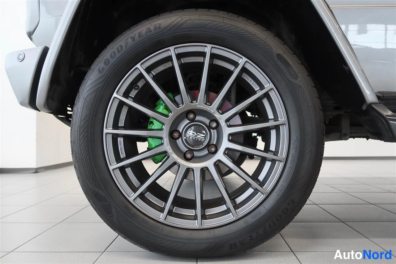 Yksityiskohta: Auton rengas ja OZ Racing -vanne lähikuvassa, vihreä jarrusatula näkyy pölysuojan läpi.