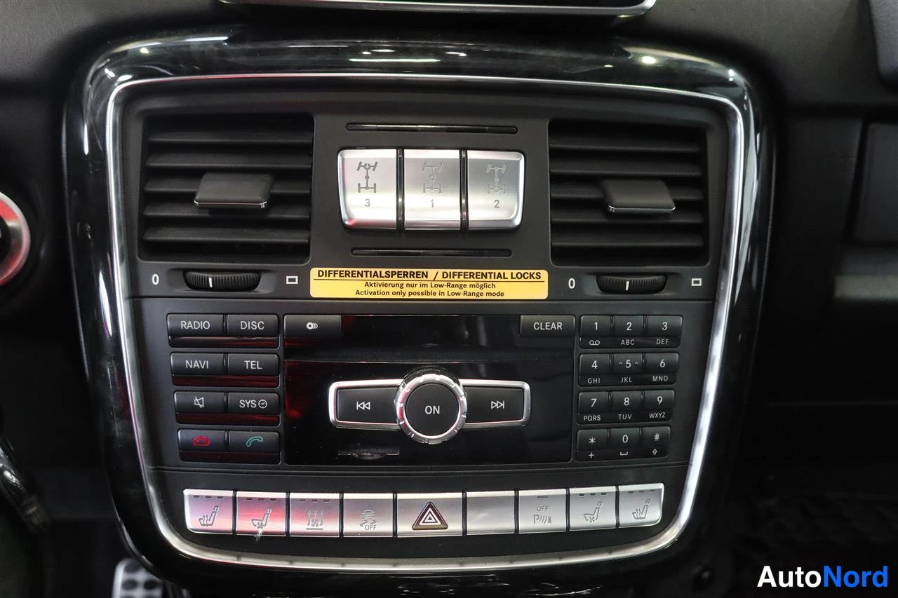 Muu: Mercedes-Benzin keskinäsen konsolin paneeli, jossa ovat radio-, navi- ja puhelinpainikkeet, numeronäppäimistö, ON-säädin sekä kolme lukkiudegettextä-kuvaa ja ke