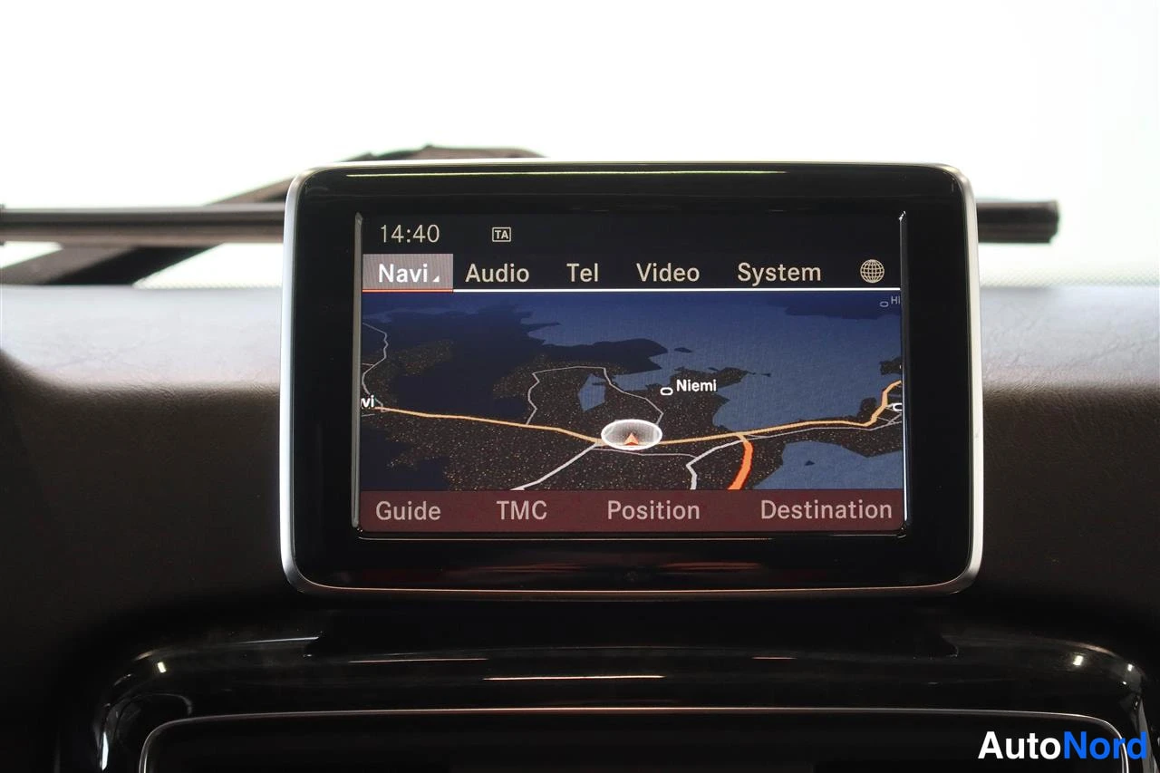 Yksityiskohta: Kojelautaan sijoitettu nykyisen Mercedes-Benzin medianäyttö, jolla näkyy navigaation kartta; valikossa Navi, Audio, Tel, Video, System.