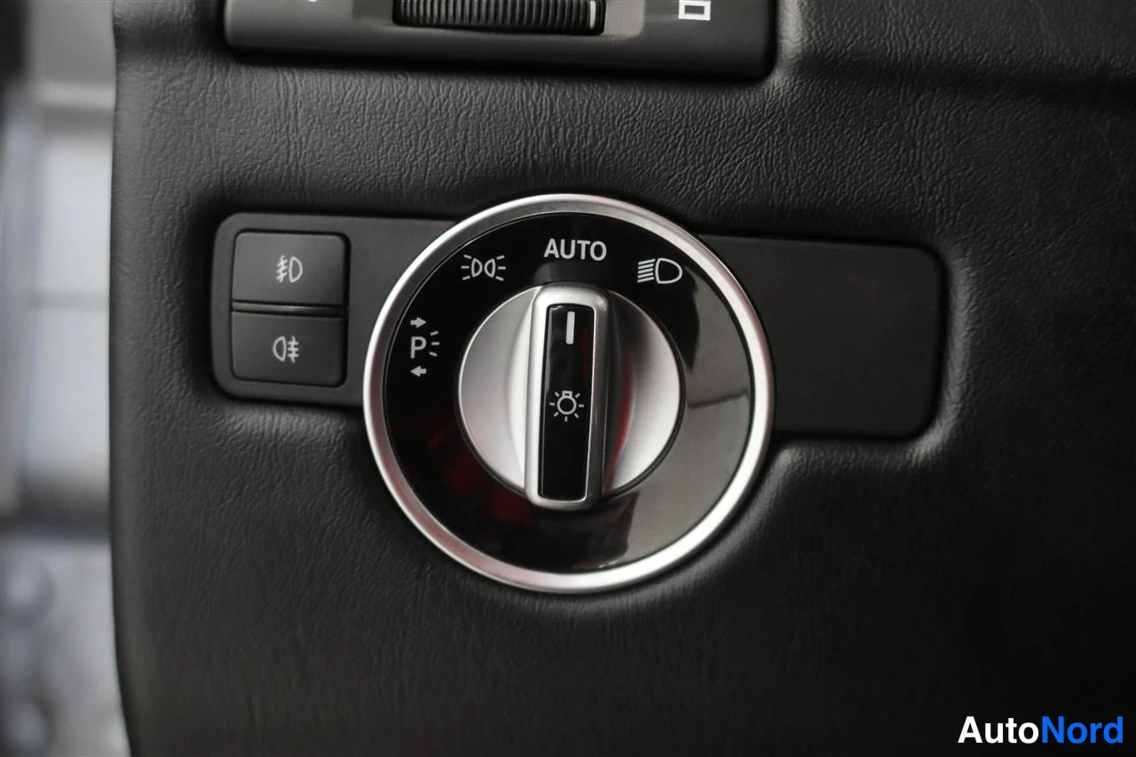 Muu: Auton kojelaudan valokytkin, jossa AUTO-merkintä ja sumuvalojen painikkeet mustassa sisäpanelissa.